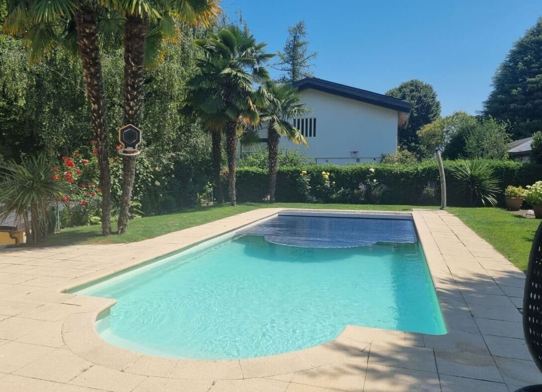 Piscine sécurisée avec une couverture de protection dans un jardin arboré