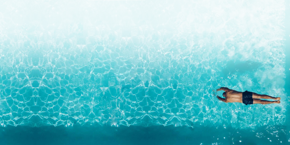 Vue aérienne d’une piscine aux eaux cristallines avec un nageur, symbole de bien-être et de détente